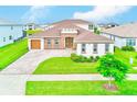 An attractive single-Gathering home with three-car garage, beautiful stone accents, and well-manicured landscaping at 8717 Sanders Tree Loop, Wesley Chapel, FL 33545