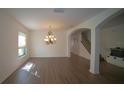 Bright living room featuring modern chandelier, hardwood floors, and open access to a staircase at 1708 Abbey Trace Dr, Dover, FL 33527