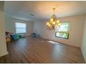 Spacious living room illuminated by natural light, featuring a decorative chandelier and hardwood floors at 1708 Abbey Trace Dr, Dover, FL 33527