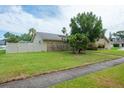 Spacious front yard featuring lush green grass, privacy fence, and mature trees creating a serene outdoor space at 2421 Eagle Chase Dr, Palm Harbor, FL 34683