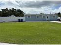 Charming single-story home with a well-kept lawn, white fence, and a light blue exterior at 2927 W Henry Ave, Tampa, FL 33614