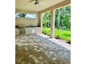 Outdoor kitchen with stone backsplash and stainless steel grill, overlooking a manicured lawn at 4800 Hickory Oak Dr, Brooksville, FL 34601