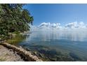 Picturesque waterfront view with clear water, natural stone retaining wall, and a serene sky with fluffy clouds at 6210 Bayshore Blvd, Tampa, FL 33611