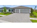 Charming one-story home boasts a 3-car garage and well-manicured landscaping along a brick paver driveway at 2743 Winding Creek Trl, North Port, FL 34289