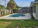 Backyard pool with concrete decking, surrounded by a privacy fence and lush greenery; perfect for relaxation at 1596 S Evergreen Ave, Clearwater, FL 33756