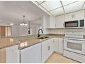 Bright kitchen with white cabinetry, granite countertops, and stainless steel sink looking to the living room at 316 Kelsey Way # 316, Sun City Center, FL 33573