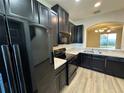 Efficient kitchen design with black appliances, laminate countertops and arch to living area at 8819 Walnut Gable Ct, Riverview, FL 33578