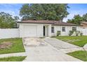 View of a charming single-story home with white fence, stone accent wall and attached garage at 4410 Lurline Cir, Tampa, FL 33610