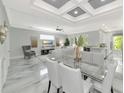 Open concept dining room with glass table, white chairs, and modern lighting at 7730 Hidden Creek Loop # 101, Lakewood Ranch, FL 34202