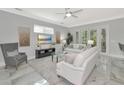 Bright living room with white sofas, gray chair, and large TV at 7804 Hidden Creek Loop # 101, Lakewood Ranch, FL 34202
