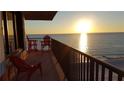 Gorgeous sunset view over the ocean from the condo balcony with red chairs, creating a peaceful ambiance at 15316 Gulf Blvd # 604, Madeira Beach, FL 33708
