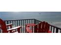 Relaxing ocean view from the condo's balcony with two red Adirondack chairs and a small table at 15316 Gulf Blvd # 604, Madeira Beach, FL 33708