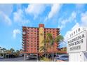 Exterior view of Madeira Towers, showing the architecture, parking, and signage against a sunny sky at 15316 Gulf Blvd # 604, Madeira Beach, FL 33708