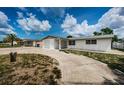 Ranch style home with white brick exterior, attached garage, and landscaped yard at 3423 Eisenhower Dr, Holiday, FL 34691