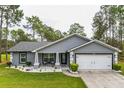 Gray house with white garage and well-manicured lawn at 12476 Jaybird Rd, Weeki Wachee, FL 34614