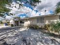 Tan single story house with a blue door, gravel driveway, and lush landscaping at 16003 2Nd E St, Redington Beach, FL 33708