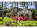 White gazebo nestled in a garden with vibrant red plants at 761 Soundview Dr, Palm Harbor, FL 34683