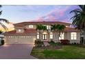 Stunning two-story home with tile roof, three-car garage, and beautiful landscaping at dusk at 17371 Kennedy Dr, North Redington Beach, FL 33708