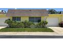Front view of a yellow house with attached garage and well-maintained lawn at 7057 Versailles N # 15, Pinellas Park, FL 33781