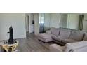 Living room featuring a gray sectional sofa and gray-toned wood-look flooring at 1153 Tamarac Dr, Holiday, FL 34690
