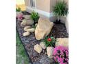 Landscaped garden with large rocks, colorful flowers, and lush greenery at 10124 Heathcliff St, Spring Hill, FL 34608