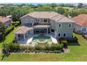 Aerial view of a home featuring a pool, spa, covered patio, and balcony overlooking a green backyard at 898 Skye Ln, Palm Harbor, FL 34683