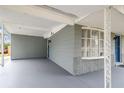 Spacious carport area with a covered roof, grey concrete flooring, and a protective barrier on the left side at 2305 N Tampania Ave, Tampa, FL 33607