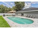 Inviting kidney-shaped pool with gray stone patio and seating at 1729 Oakwood Estates Dr, Plant City, FL 33563