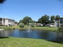 Community pond with fountain, grassy areas, and nearby buildings at 940 Virginia St # 107, Dunedin, FL 34698