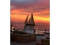 Stunning sunset view over the ocean, sailboat in the distance, and residents enjoying the beachfront pool at 450 S Gulfview Blvd # 1105, Clearwater Beach, FL 33767