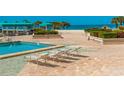 Inviting community pool featuring comfortable lounge chairs and lush landscaping with ocean view at 1380 Gulf Blvd # 307, Clearwater Beach, FL 33767