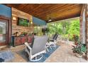 Cozy screened porch with wood ceiling, stone wall, comfortable seating and outdoor views at 3204 Polo Pl, Plant City, FL 33566