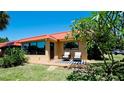 Exterior view with a seating area on the front lawn and red metal roof in a tropical setting at 4216 La Costa Cv # 4216, Bradenton, FL 34210
