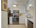 Bright kitchen with white cabinets, stainless steel appliances, and light tile floors at 6428 Gloria Dr # 15, New Port Richey, FL 34653