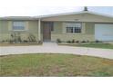 Ranch style home with green exterior, landscaping, and a paved driveway at 4102 Darlington Rd, Holiday, FL 34691