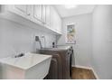 Bright laundry room with white cabinets, a utility sink, and modern appliances at 2499 Indigo Dr, Clearwater, FL 33763