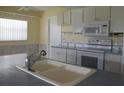 White kitchen with double sink, built-in microwave, and an electric range at 4251 100Th N Ave # 2, Pinellas Park, FL 33782