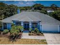 Inviting single-story home featuring a manicured lawn and tropical landscaping, enhanced by a two-car garage at 1032 Rosetree Ln, Tarpon Springs, FL 34689