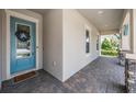 Inviting front porch featuring stone detailing, a blue door with wreath, and decorative brick flooring at 16701 Vibrato Ln, Land O Lakes, FL 34638