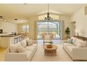 Bright living room with neutral furniture, modern chandelier, and sliding doors to the outdoor patio at 19830 Ellendale Dr, Land O Lakes, FL 34638