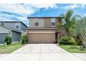 Two-story house with a beige exterior, two-car garage, and landscaping at 7417 Evening Primrose Ct, Tampa, FL 33619