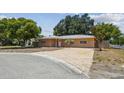 Tan single story house with a paved driveway and landscaping at 1660 San Helen Dr, Dunedin, FL 34698