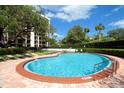 Beautiful kidney-shaped community pool with lounge chairs and manicured landscaping on a sunny day at 150 Belleview Blvd # 704, Belleair, FL 33756
