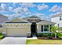 One-story house with stone accents, two-car garage, and lush landscaping at 30964 Penny Surf Loop, Wesley Chapel, FL 33545