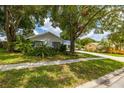 White house with blue shutters, surrounded by lush greenery at 4936 Mineola Pl, Palm Harbor, FL 34684