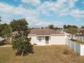 Tan house with a grey door, surrounded by a yard and trees at 14580 Wake Robin Dr, Brooksville, FL 34604