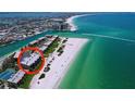 Scenic aerial view of beachfront condos with a wide sandy beach and crystal clear water at 7532 Bayshore Dr # 205, Treasure Island, FL 33706