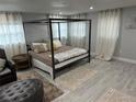 Modern bedroom features a four-poster bed, light grey walls, wood floors, sheer curtains, and neutral accents at 4438 58Th N Ave, St Petersburg, FL 33714