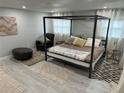 Modern bedroom features a four-poster bed, light grey walls, wood floors, sheer curtains, and neutral accents at 4438 58Th N Ave, St Petersburg, FL 33714