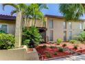 Tan Florida condo with palm trees, brick pathway, and red mulch landscaping at 7200 Ulmerton Rd # F2, Largo, FL 33771